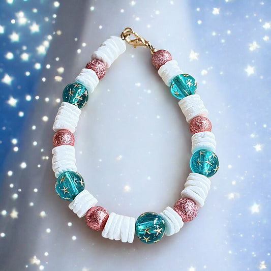 Teal and rose beaded bracelet with star-pattern beads styled in a soft, dreamy scene with light sparkles and a calm, celestial mood.