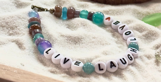 Close-up of a Live Laugh Love bracelet showing letter beads, gemstone color variations, and handmade detailing.