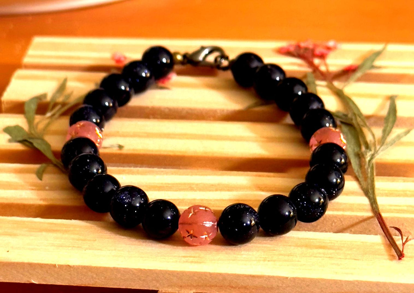 Beaded gemstone bracelet photographed from an alternate angle on a wooden surface, showing clasp and bead spacing