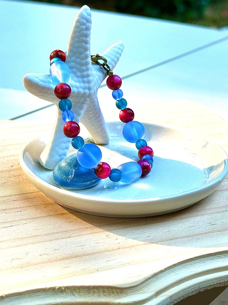 Colorful beaded bracelet on a starfish charm with a white dish on a wooden surface