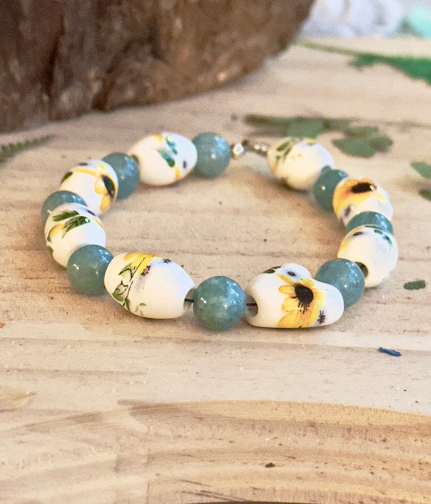 Sunflower beaded bracelet on wooden background with green leaf accents, handmade nature jewelry