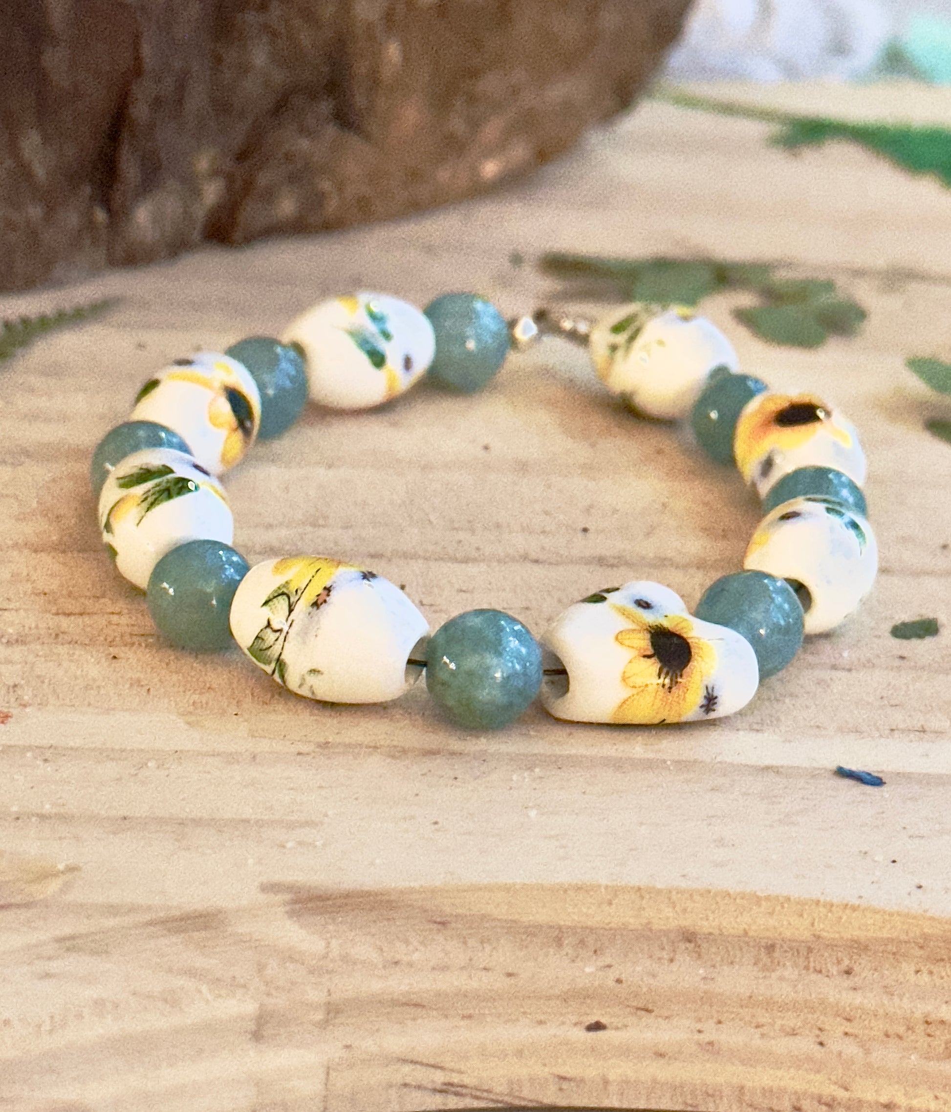 Sunflower beaded bracelet on wooden background with green leaf accents, handmade nature jewelry