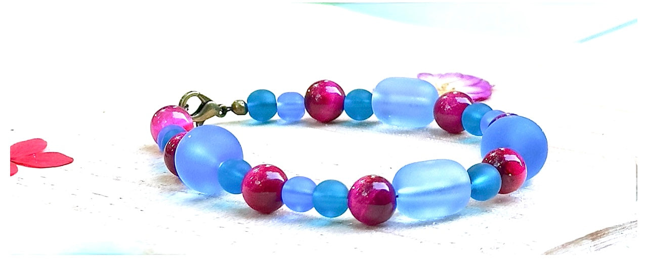 Close-up of frosted blue glass beads and glossy pink beads highlighting texture, color, and handcrafted details.