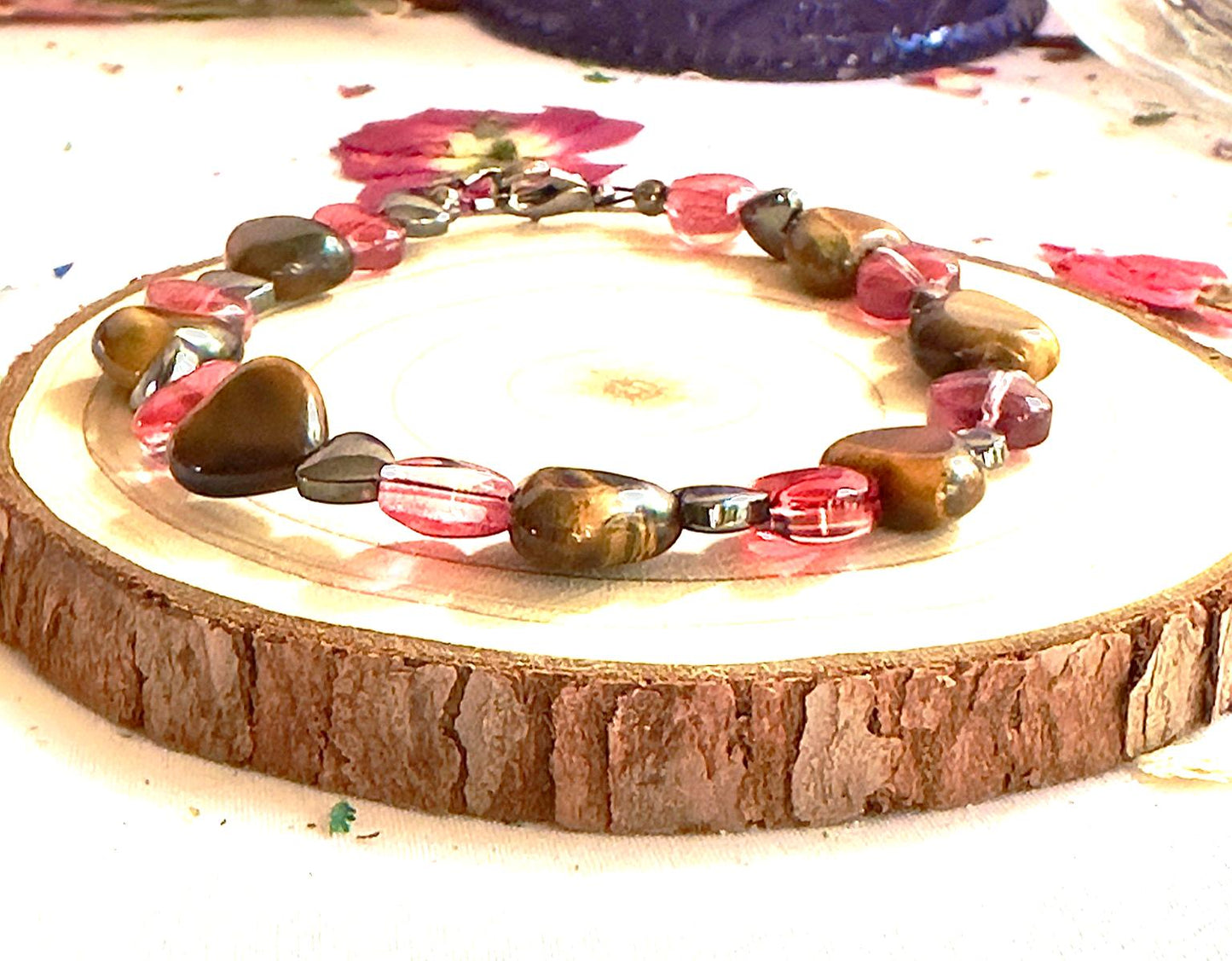 Tiger Eye heart bracelet styled on a natural wood slice with pink heart beads and earthy tones