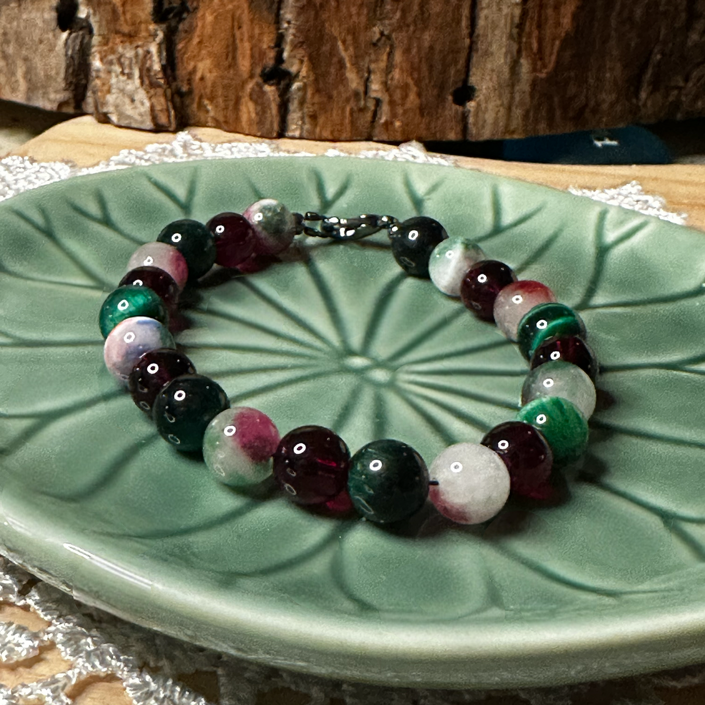 Holiday gemstone bracelet shown from a slightly different angle on a green dish, highlighting the full circular design and balanced bead arrangement.