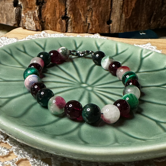 Holiday gemstone bracelet shown from a slightly different angle on a green dish, highlighting the full circular design and balanced bead arrangement.