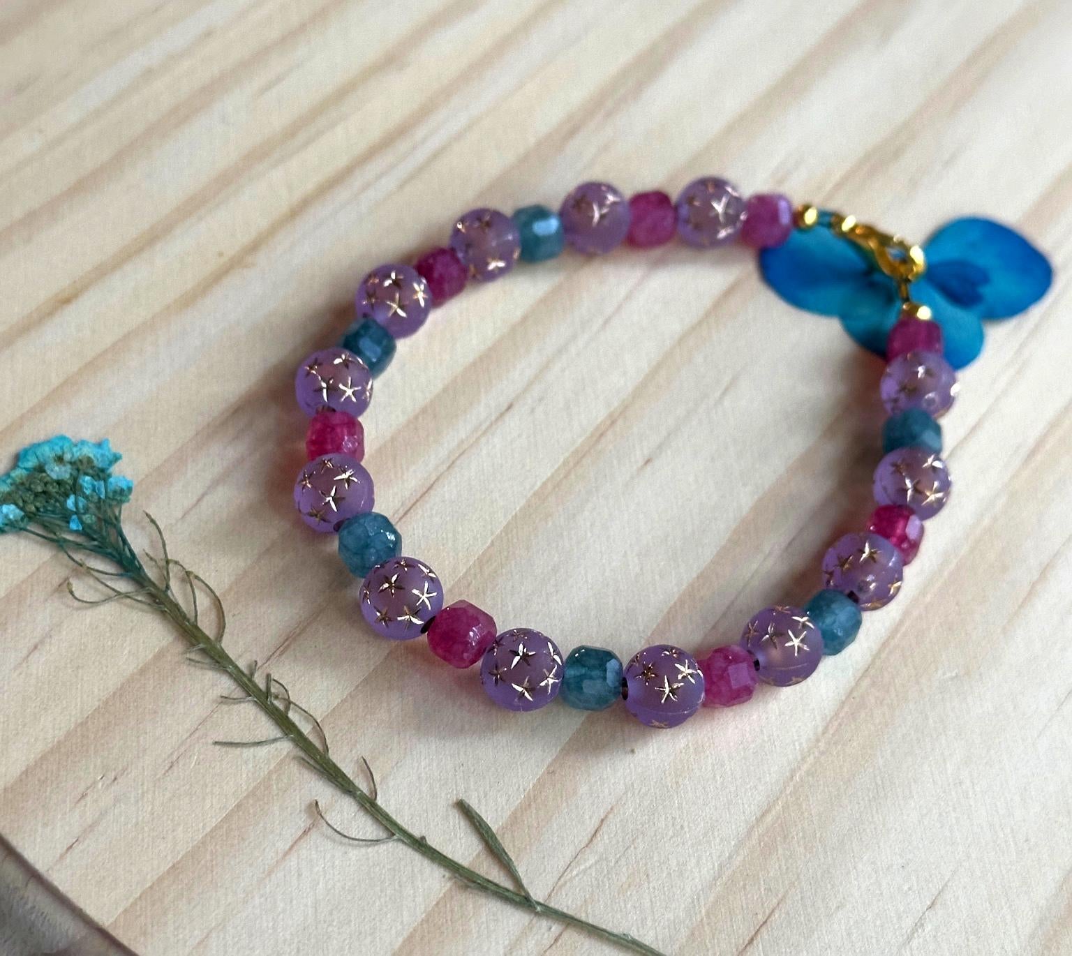 Alternate angle of a lavender and teal gemstone bracelet styled with dried florals on a wood background.