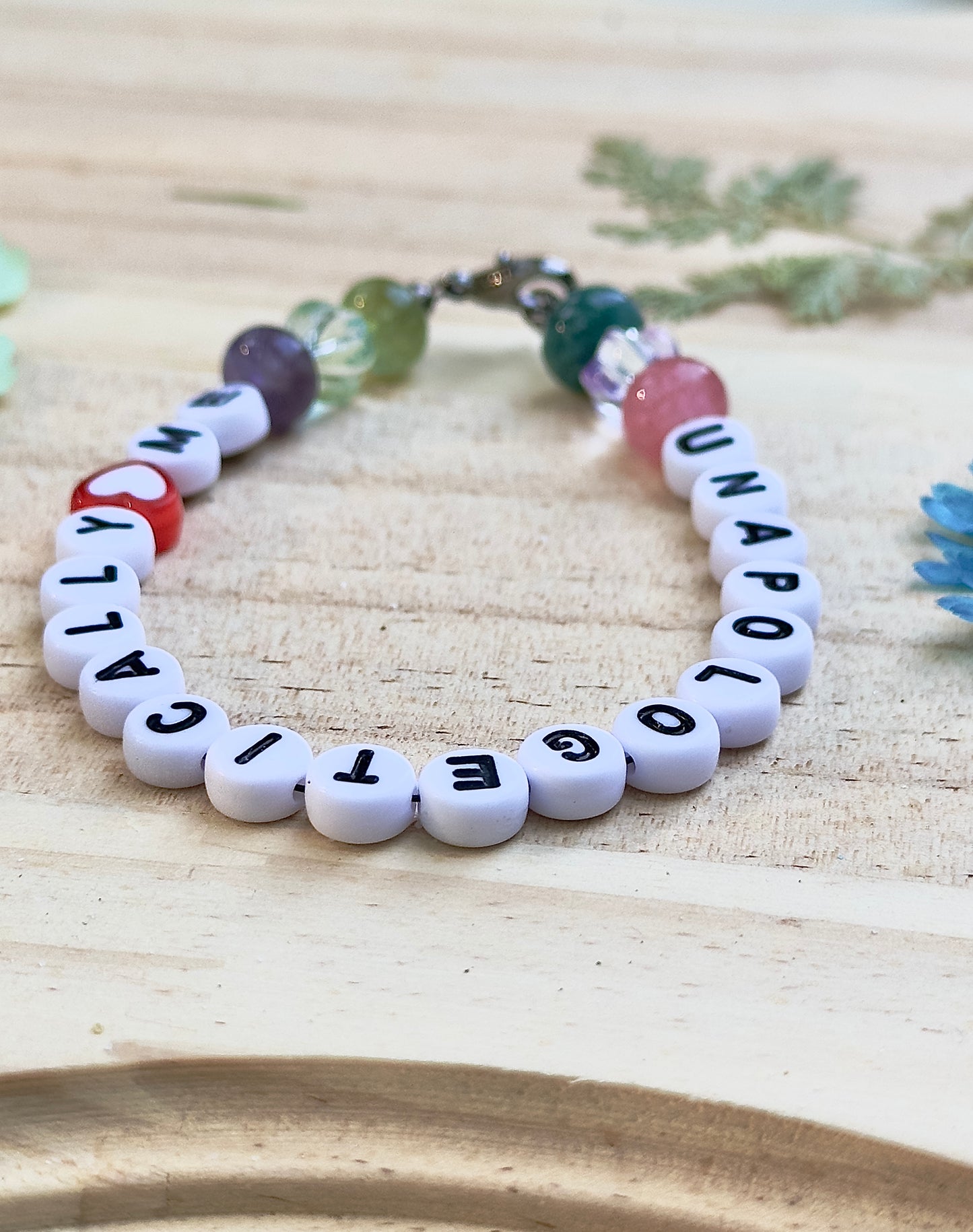 Close-up angle of an Unapologetically Me affirmation bracelet showing letter beads, heart detail, and lobster clasp.