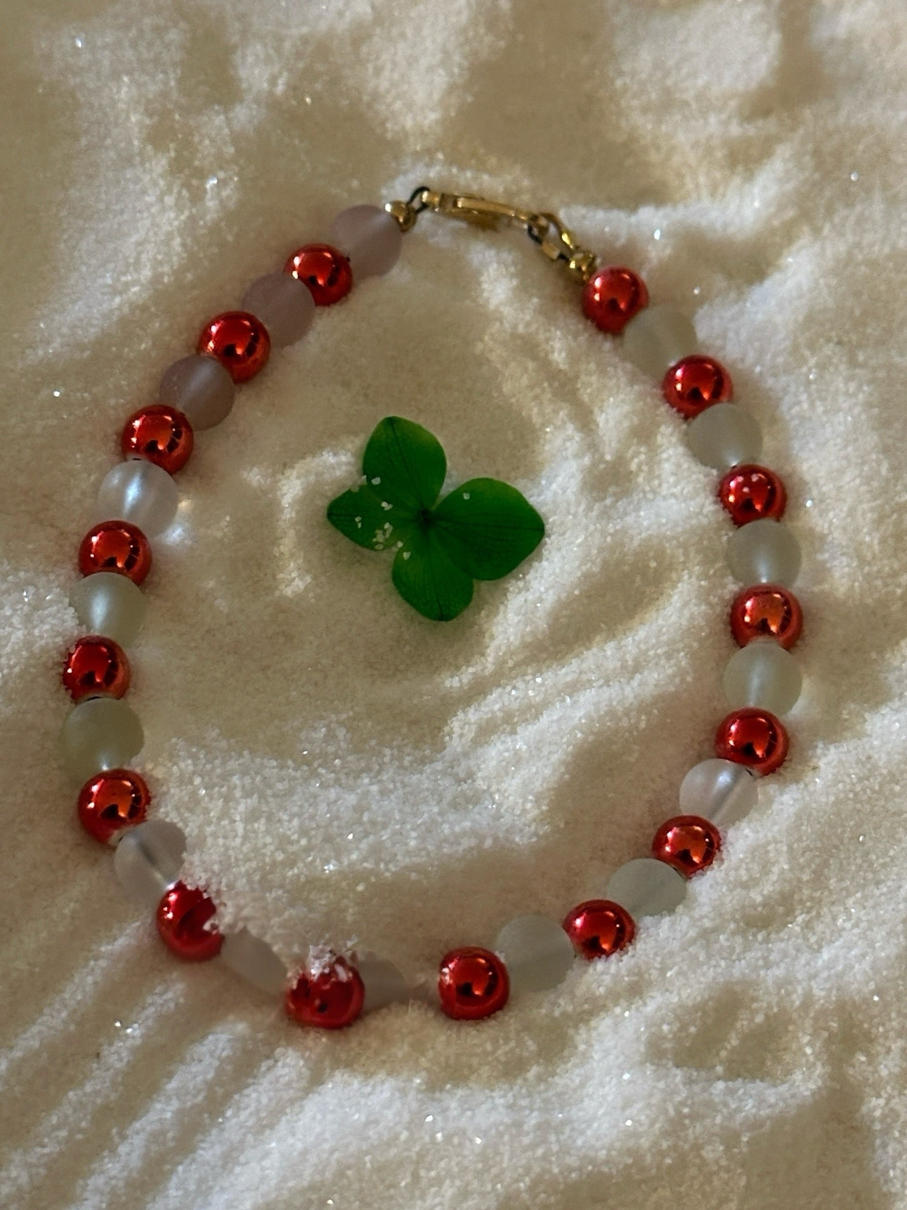 Full view of blush glass bead bracelet on sand showing size, shape, and rose-tone bead spacing.