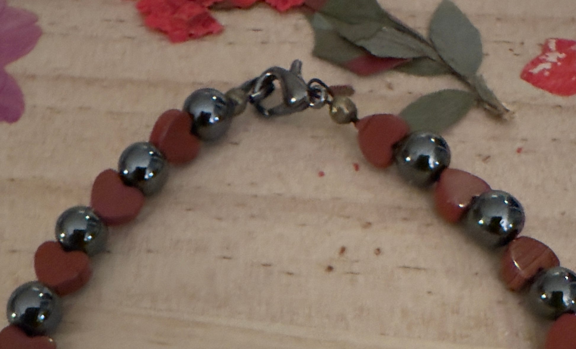 Close-up of red heart beads and polished hematite stones on the Quiet Heart handmade bracelet