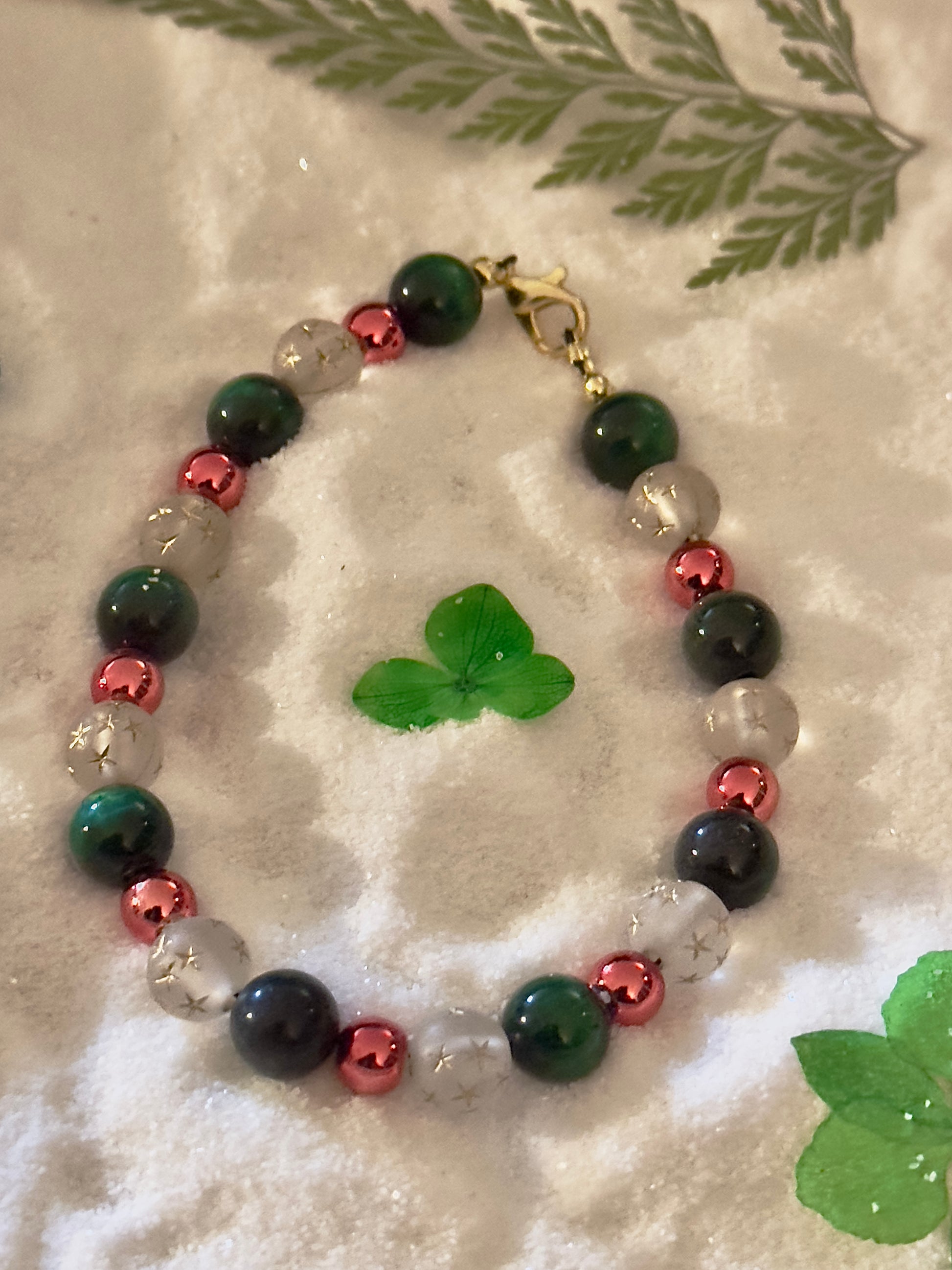 Handcrafted holiday bracelet photographed on a neutral background highlighting gemstone colors and star details.