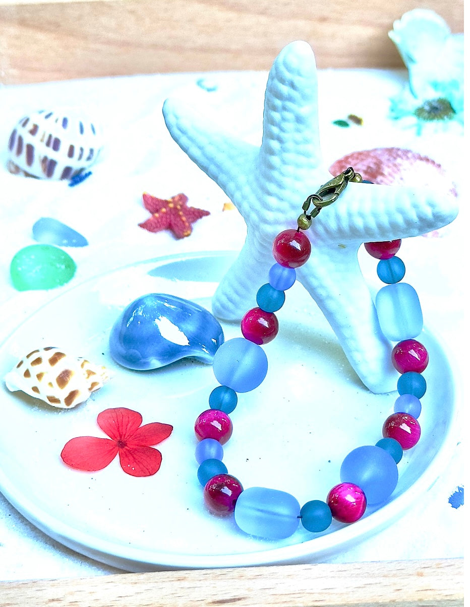 Beaded bracelet displayed on a decorative stand with coastal accents, highlighting color harmony and summer style.