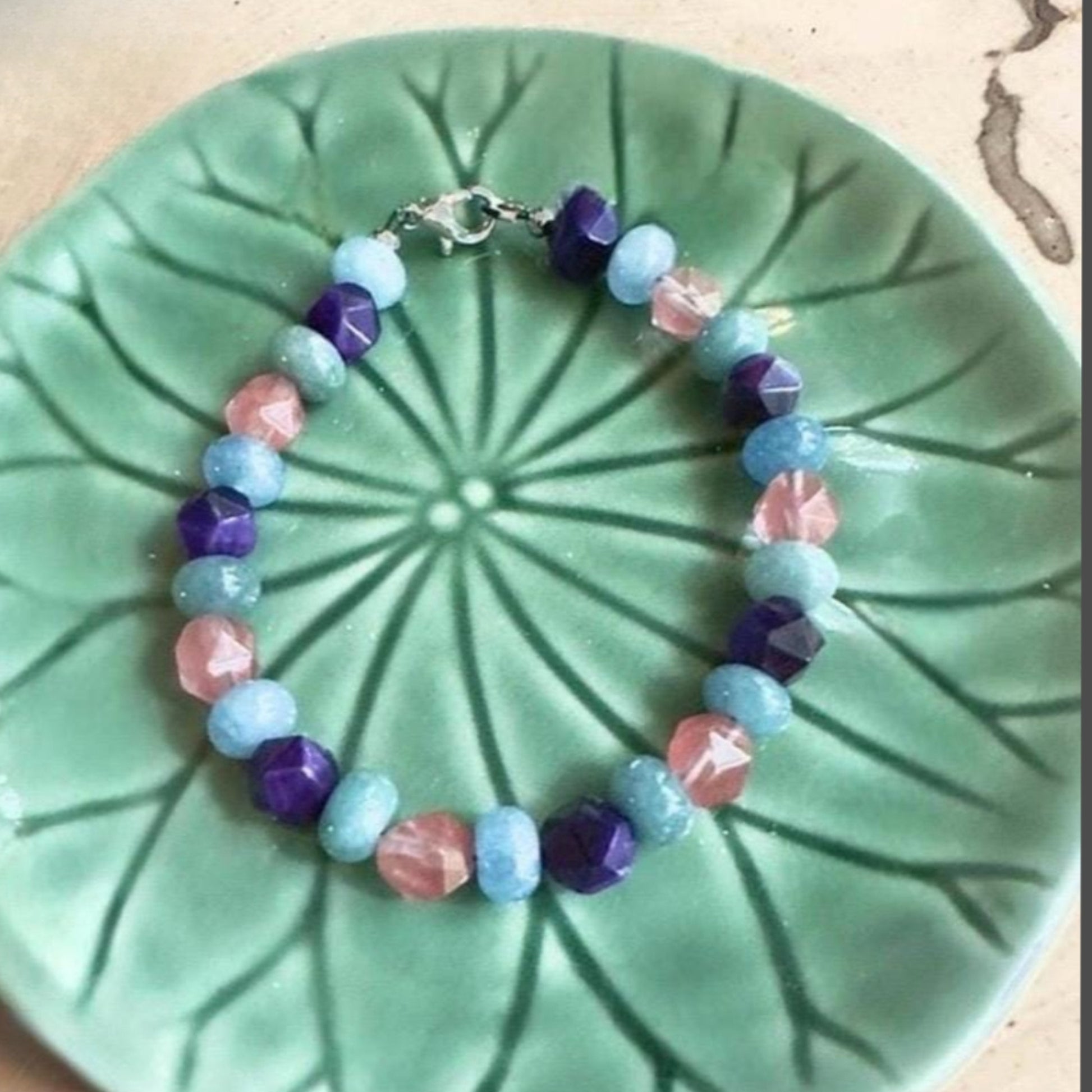 Colorful gemstone bracelet styled on a green ceramic plate, creative flat lay highlighting bead colors and handmade design