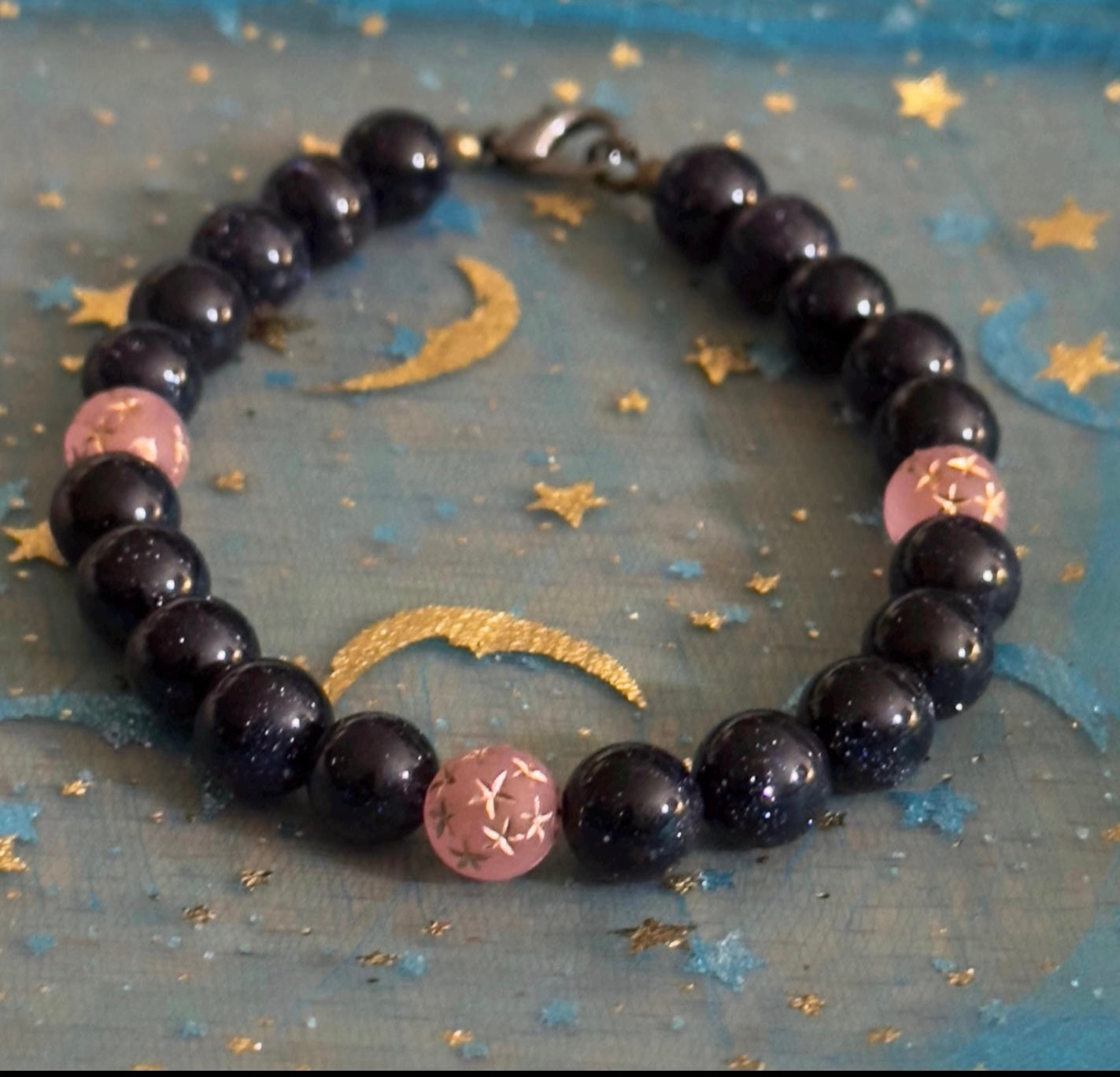 Mystical flat lay of a dark blue sandstone bracelet on a moon and stars background, styled to reflect calm, balance, and celestial energy