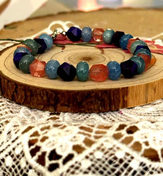 Handmade gemstone bracelet on a wood slice with vibrant multicolor beads, artistic jewelry display