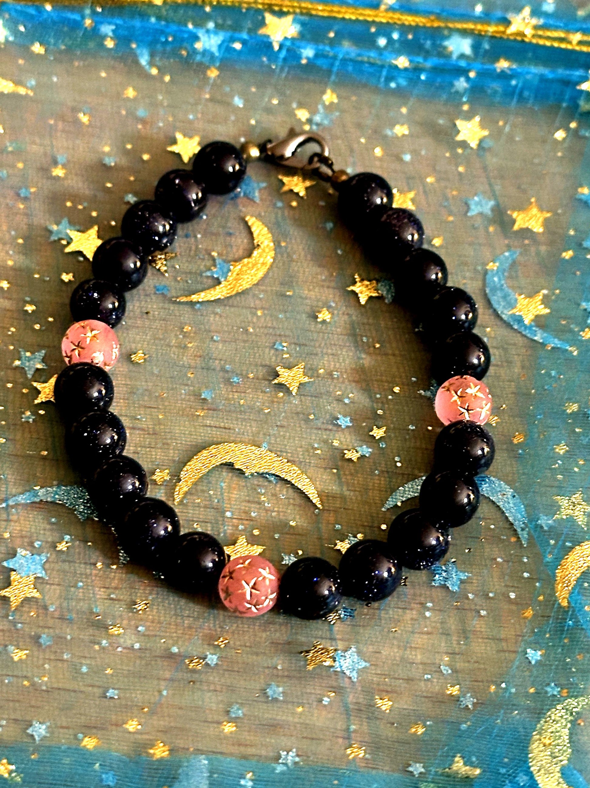 Handmade celestial bracelet styled on a starry surface with moon accents, emphasizing its night sky inspired design