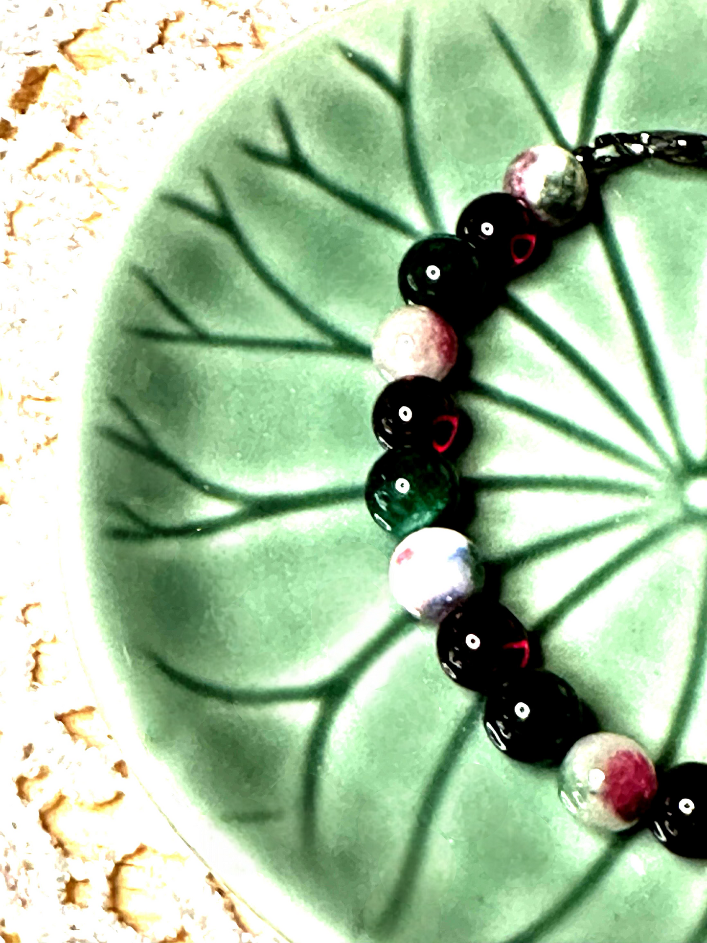 Photo 5 (Cozy Lifestyle)
Christmas Eve bracelet styled on a warm rustic surface, creating a cozy holiday atmosphere with festive red and green gemstone accents.