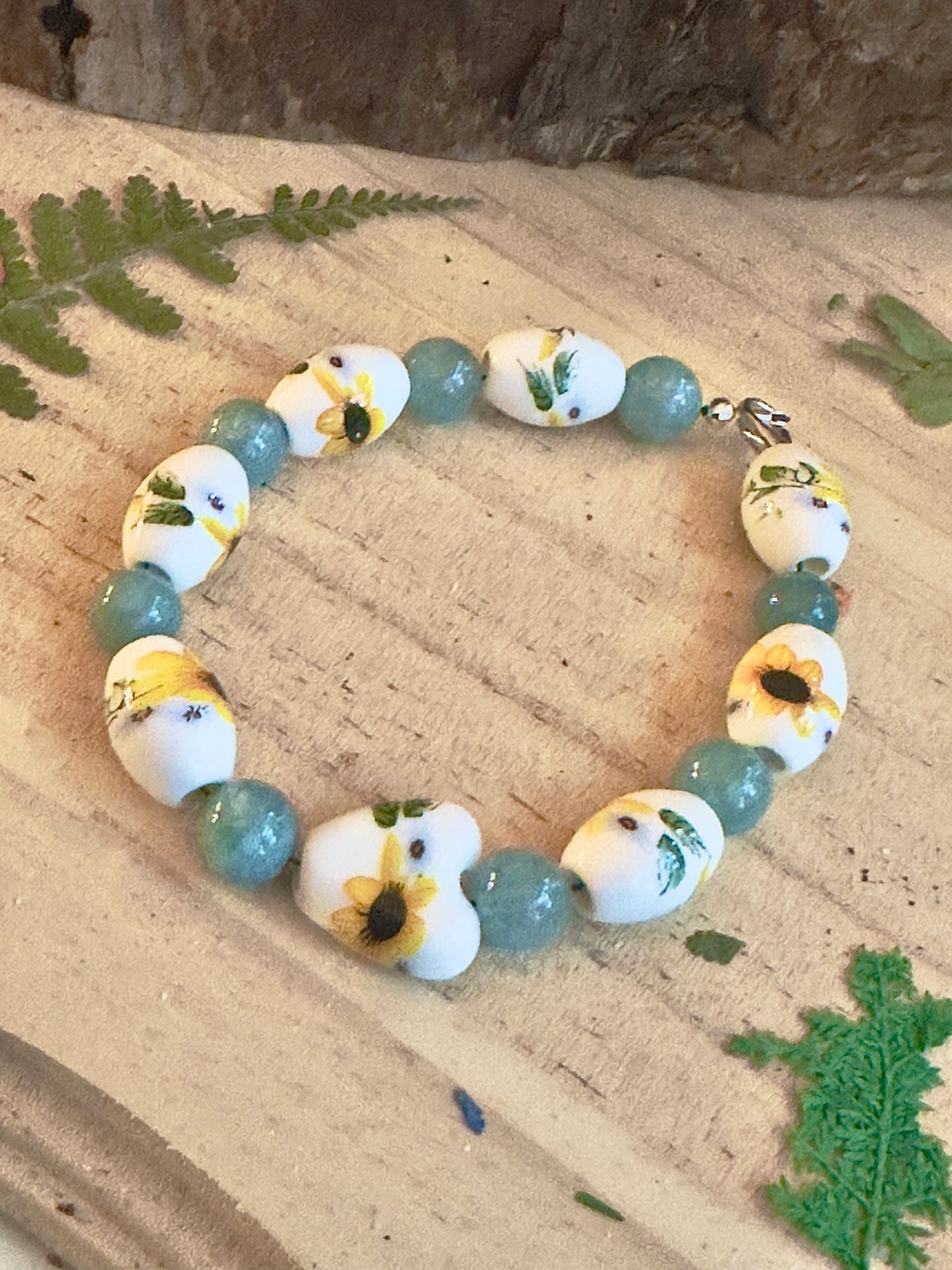 Close up of sunflower beads and teal gemstone beads on handmade bracelet, floral bead detail
