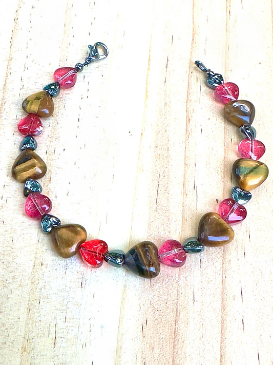 Handmade Tiger Eye and pink heart bracelet laid flat on a light neutral background, Rooted in Harmony Anchored in Love