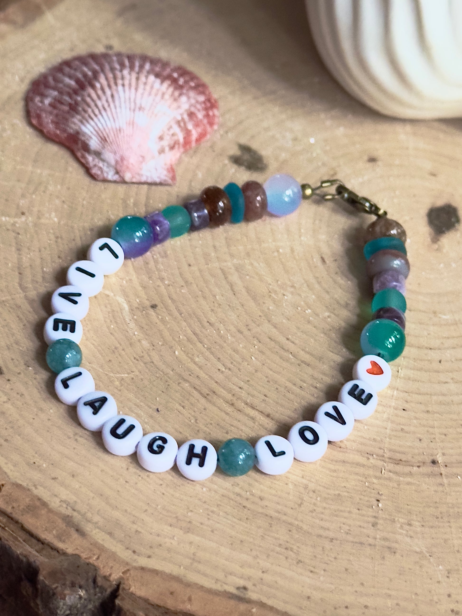 Handmade Live Laugh Love bracelet photographed in natural light with organic elements for a calming lifestyle feel.