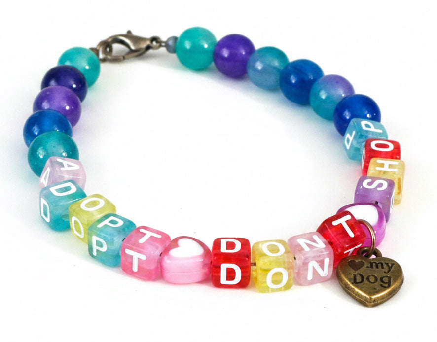 Close-up view of the Adopt Don’t Shop bracelet highlighting colorful letter beads, heart beads, and paw print charm details.