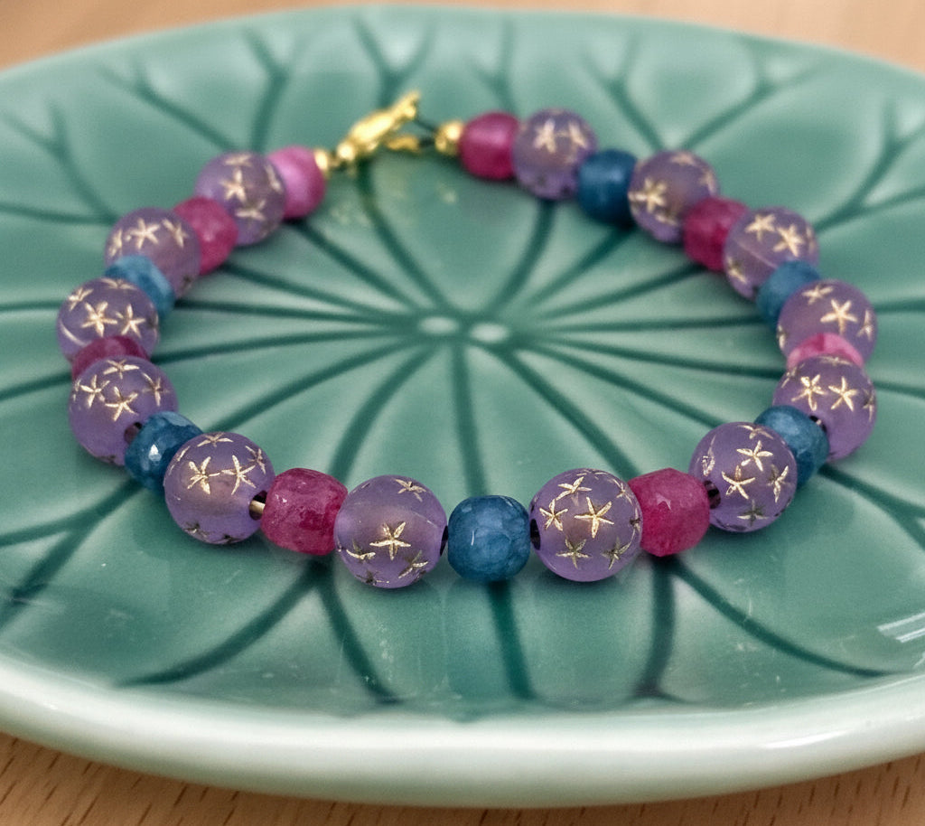 Colorful celestial gemstone bracelet displayed on green leaf dish