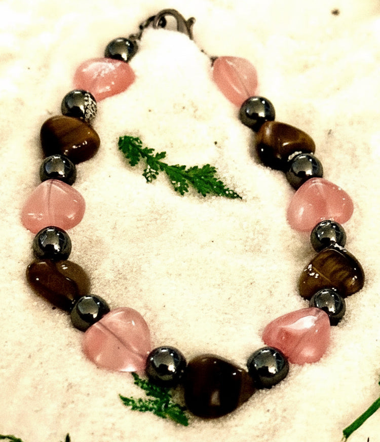 Close-up side view of rose quartz heart bracelet with tiger's eye and hematite beads.