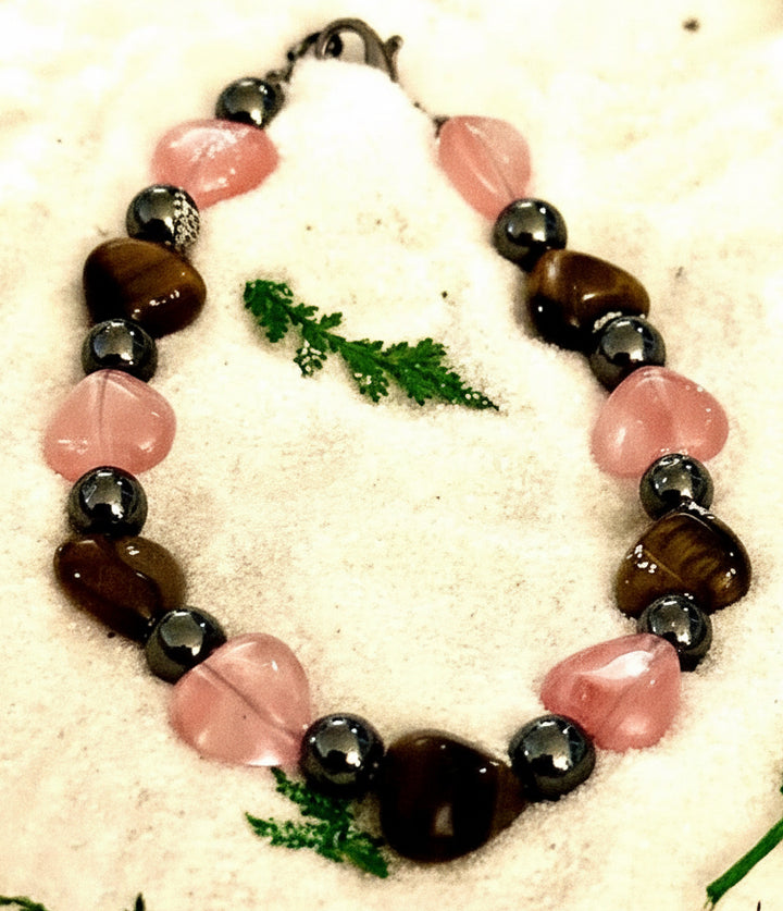 Close-up side view of rose quartz heart bracelet with tiger's eye and hematite beads.