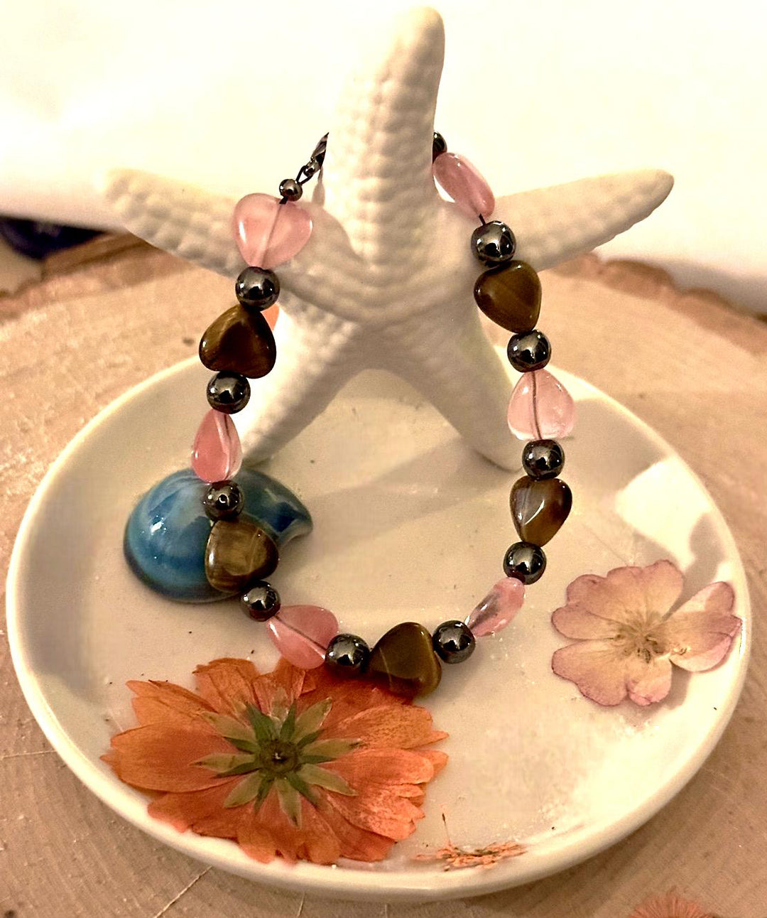 Handmade self-love bracelet displayed with coastal and floral accents.