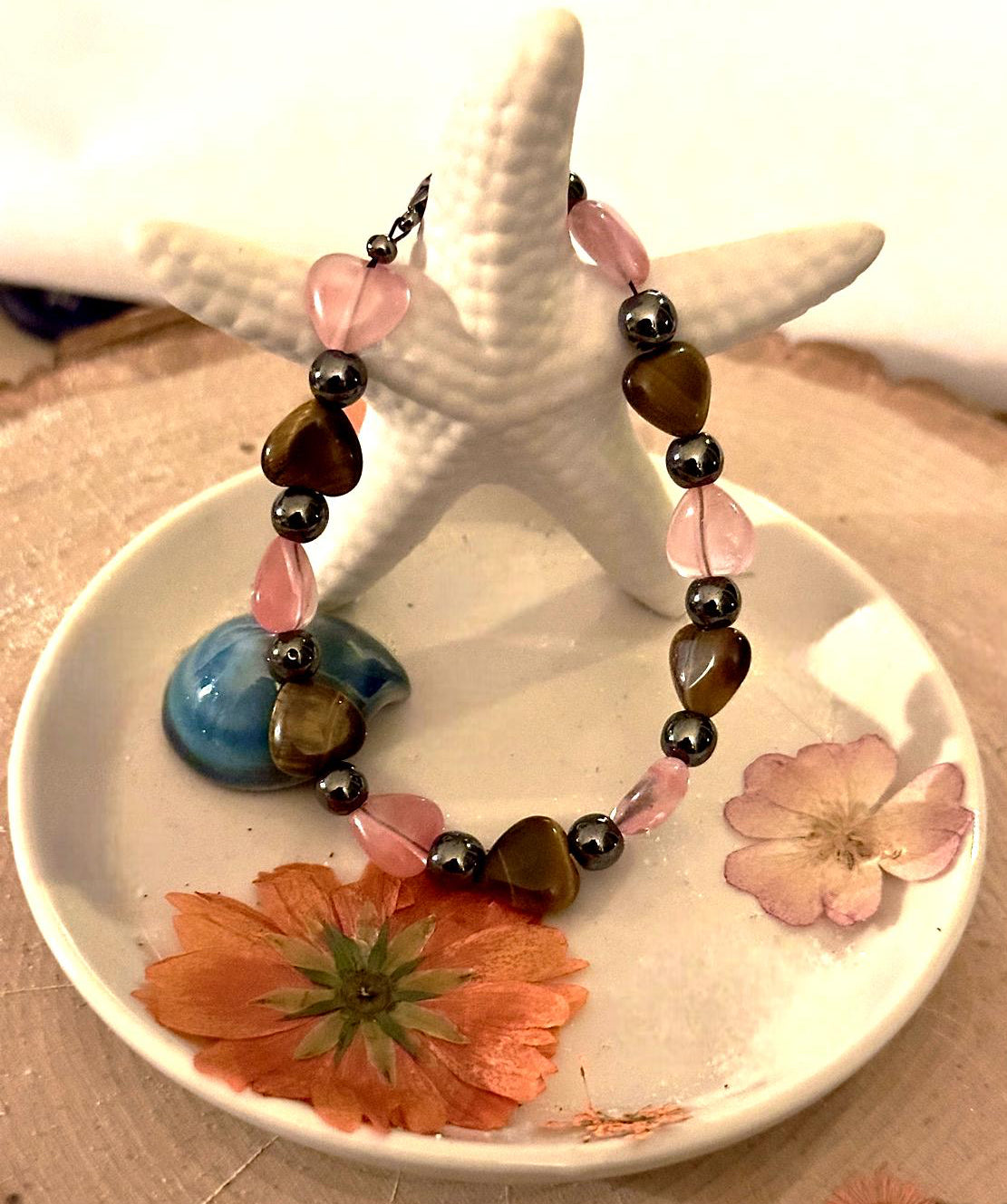 Handmade self-love bracelet displayed with coastal and floral accents.