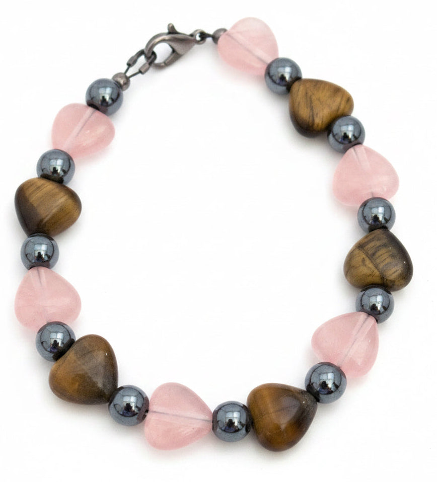 Blushing Heart Whispers handmade bracelet featuring rose quartz hearts, tiger's eye gemstones, and hematite beads on a white background.