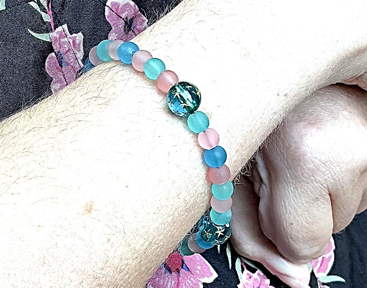 Handmade teal and pink gemstone bracelet styled on white ceramic dish with teal star accent, beach-inspired jewelry