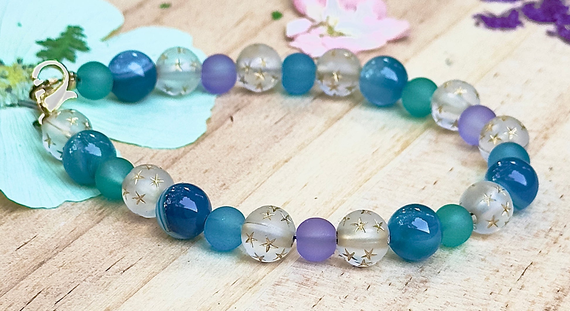 Multicolored beaded bracelet on a wooden surface with flowers