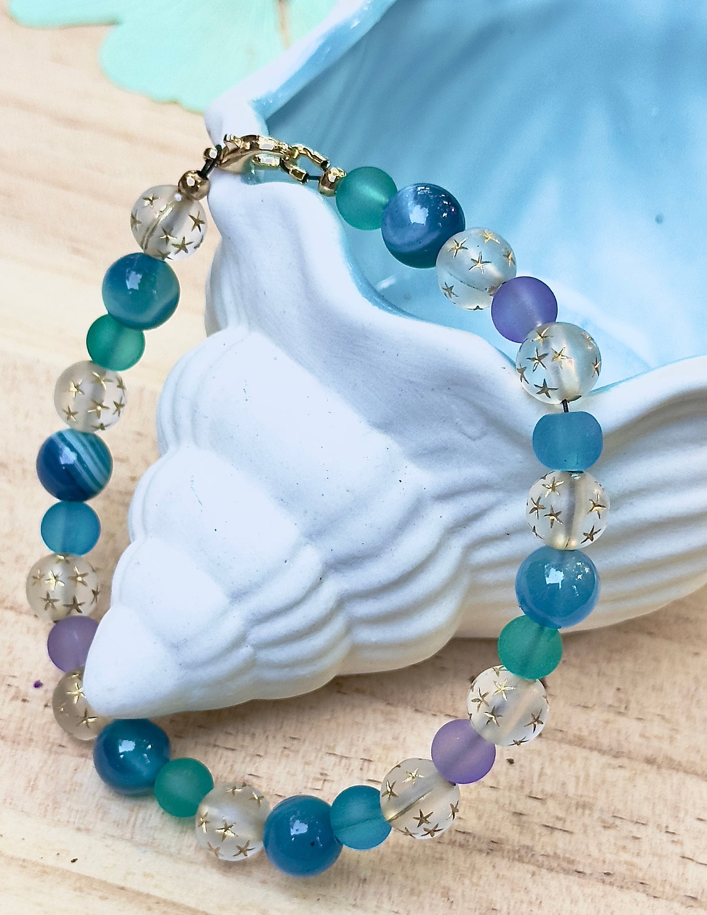 Beaded bracelet with blue and purple stones on a shell background