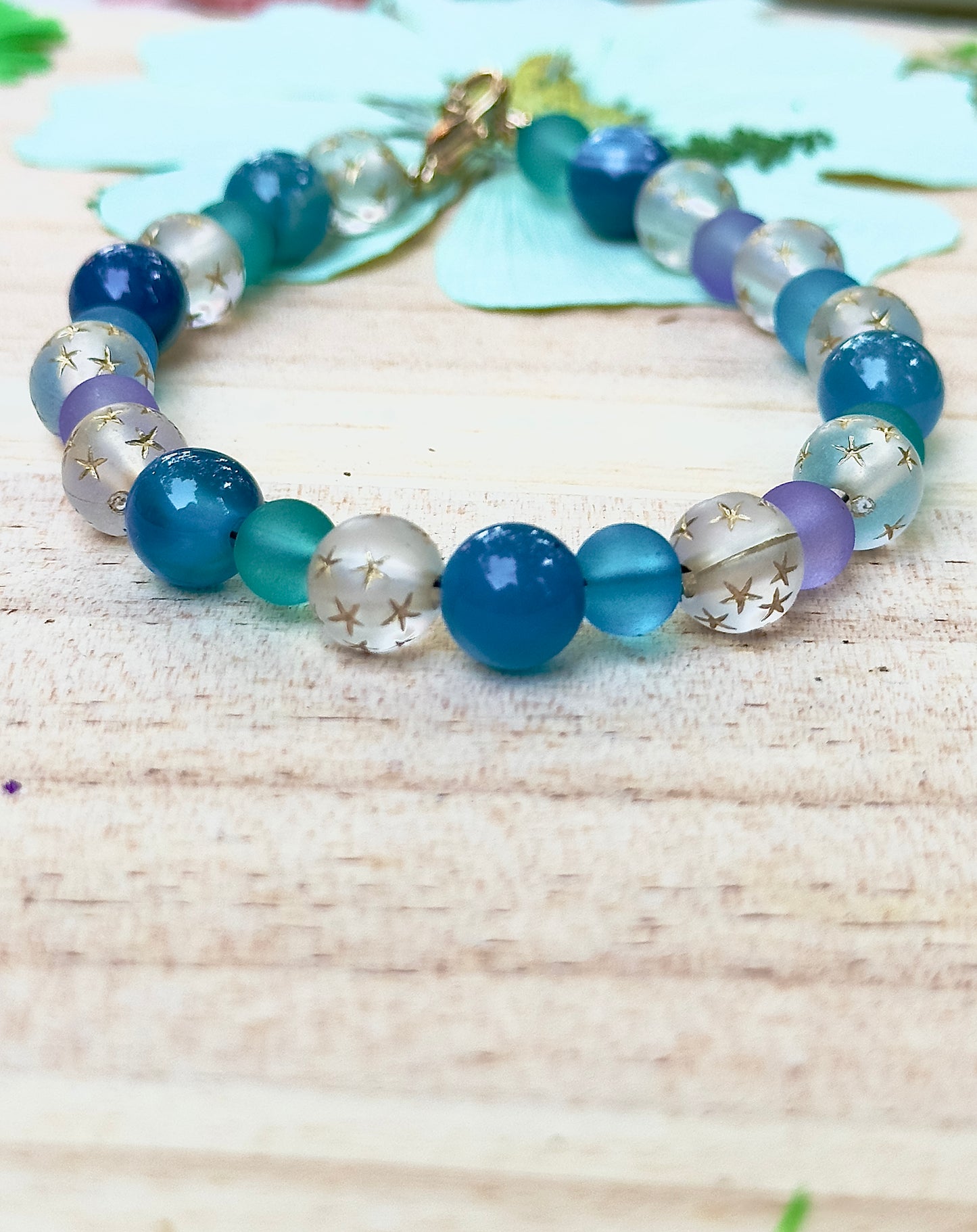 Celestial Opalite Sky bracelet styled with soft floral accents on a light wooden surface