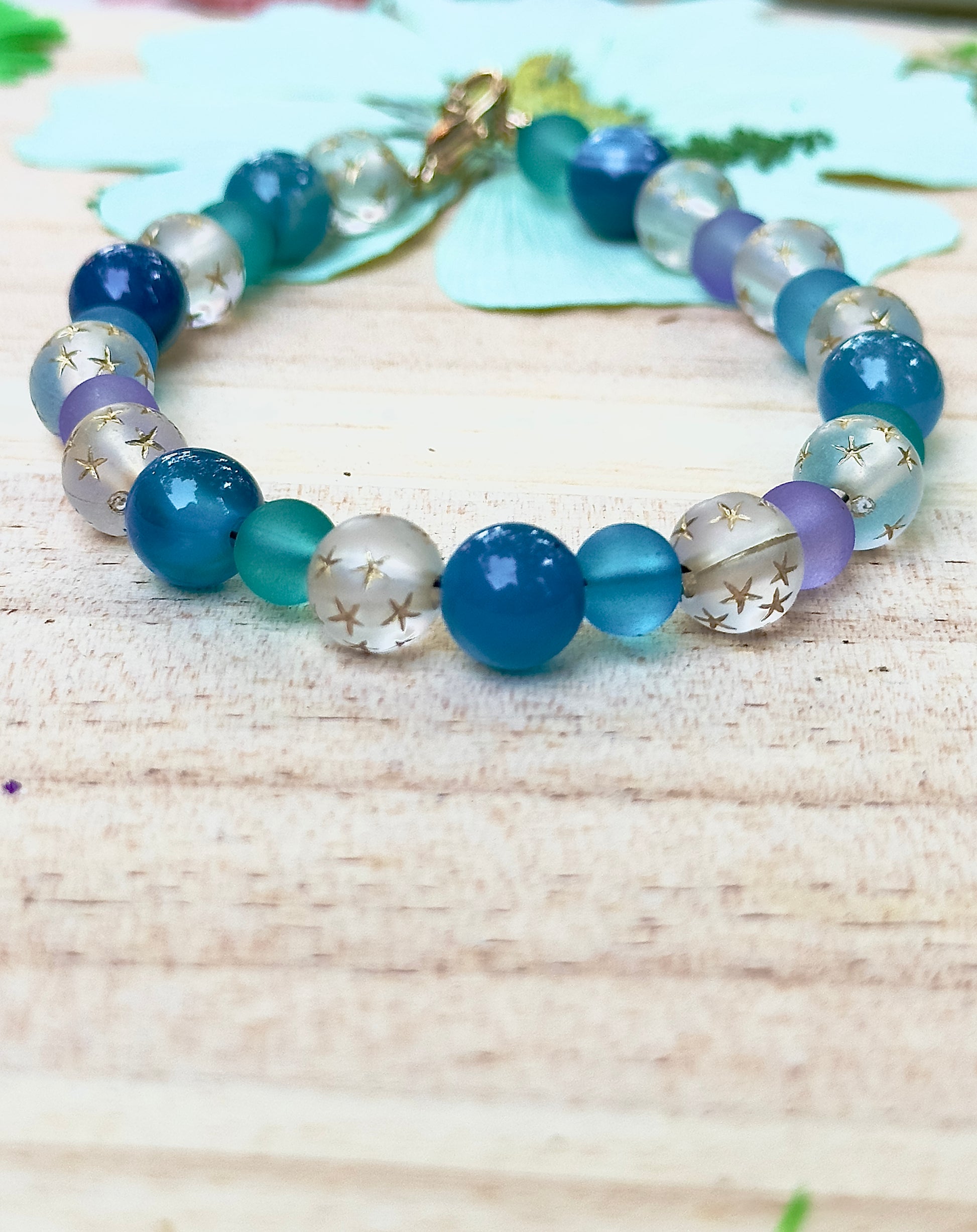 Celestial Opalite Sky bracelet styled with soft floral accents on a light wooden surface