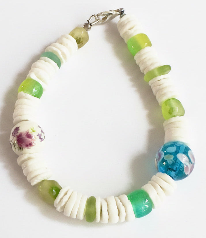 Coastline Oasis bracelet featuring white heishi beads, green glass accents, and floral ceramic beads in a nature-inspired design.
