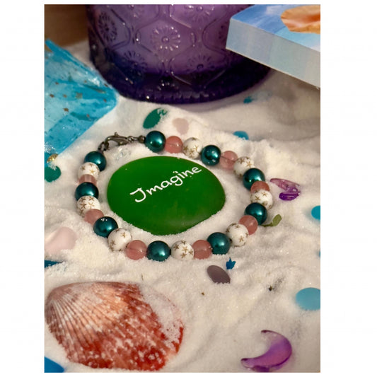 Teal and pink beaded bracelet with star details photographed on a leafy natural background, inspired by calm and nature
