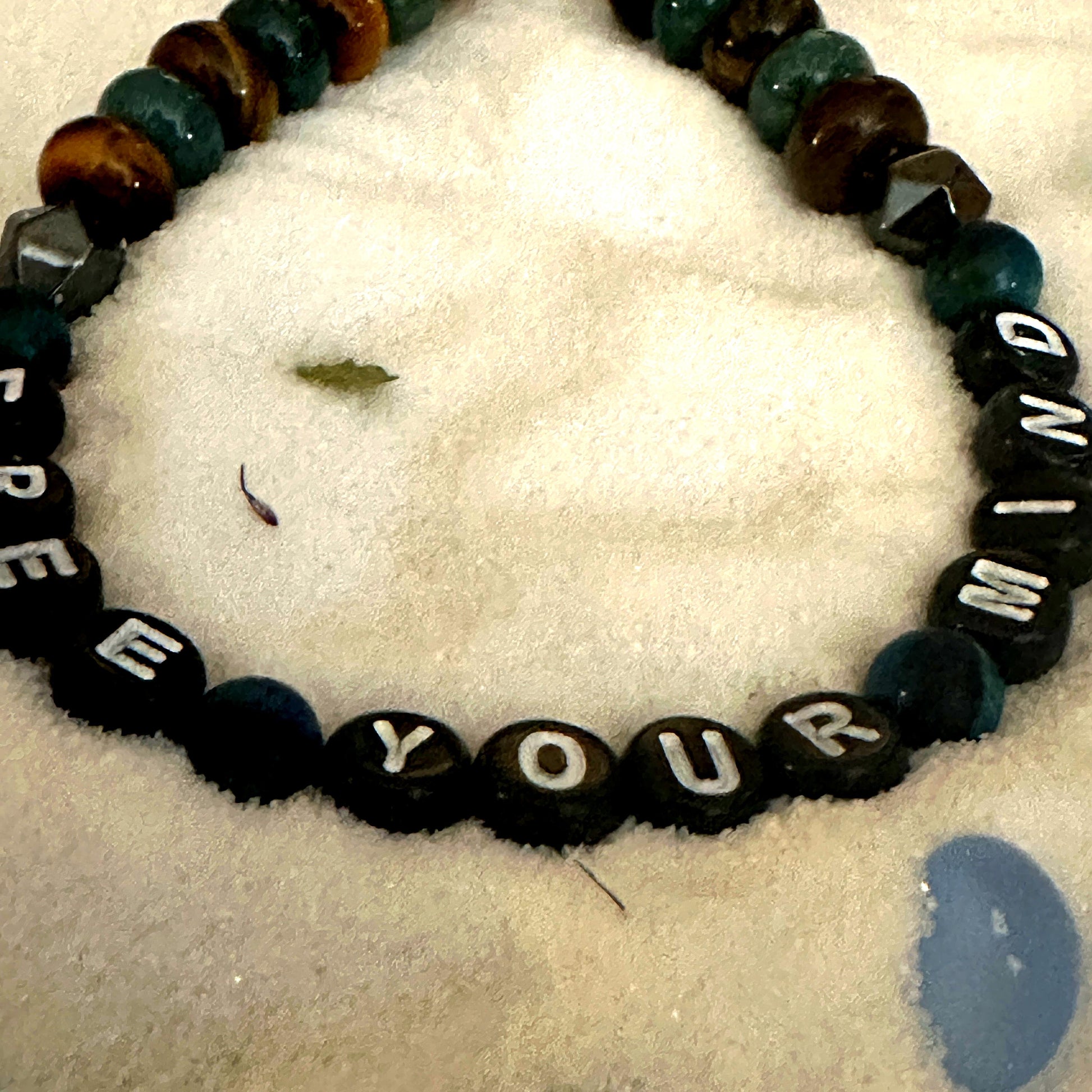 Close-up of Free Your Mind bracelet showing beaded details and lobster clasp on wood background