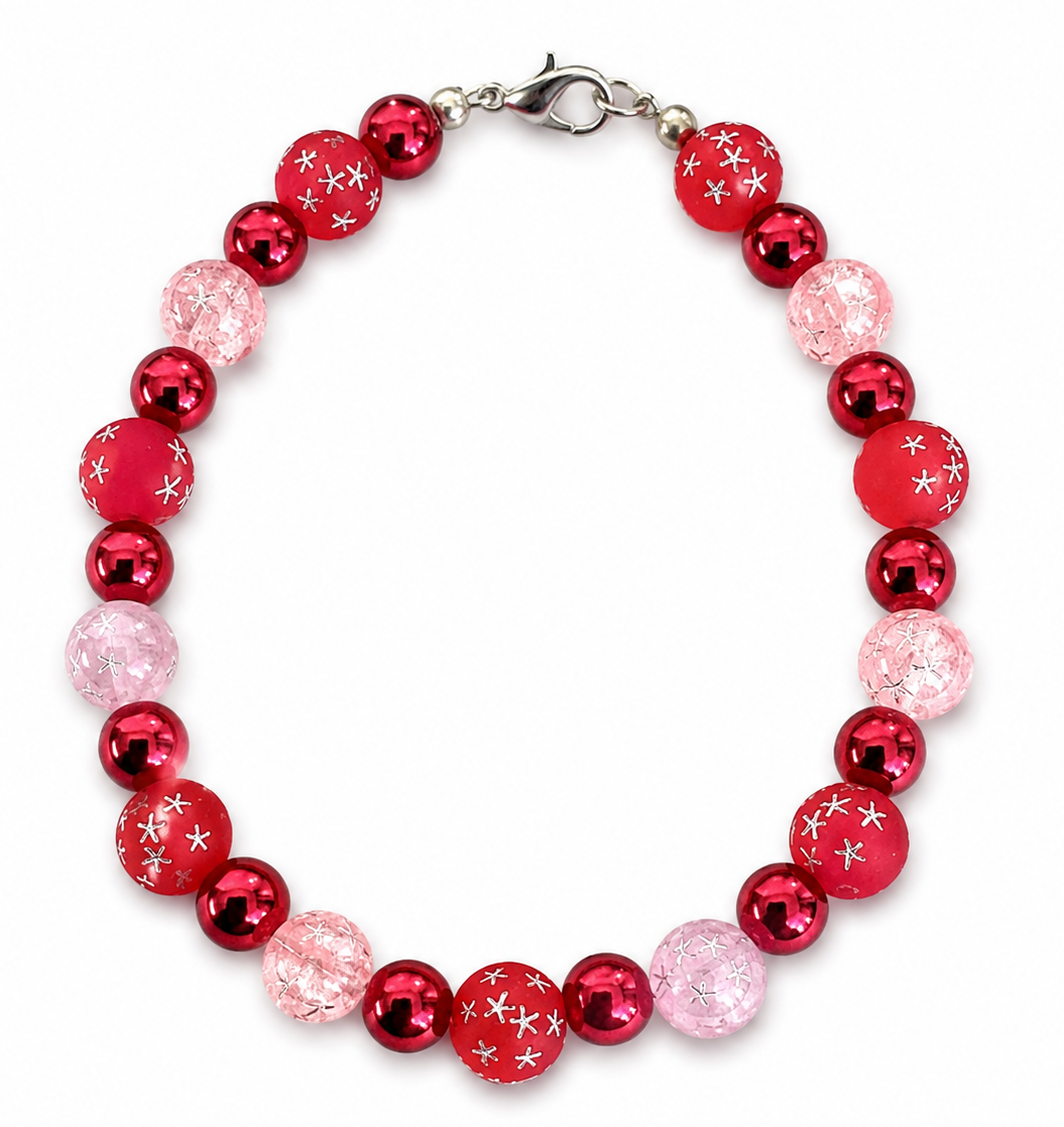    Handmade red and pink celestial beaded bracelet with crackle glass beads and silver star details on white background
