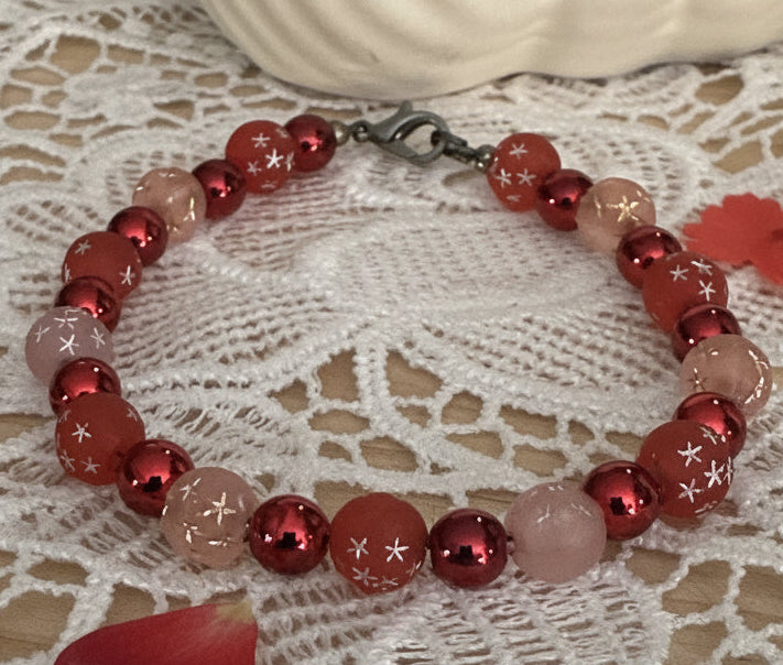     Whimsical cosmic bracelet featuring sparkle beads and crackle glass displayed with soft red heart accents on lace fabric