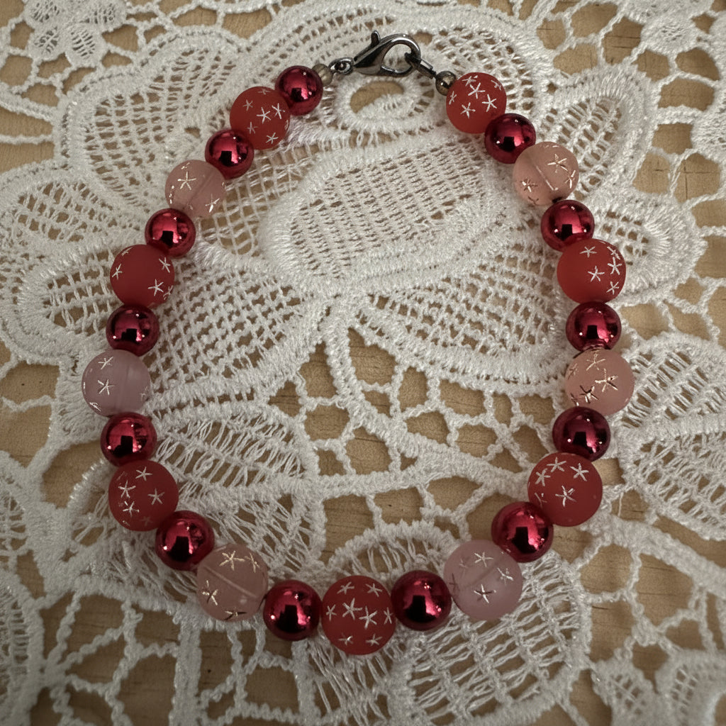     Handmade pink and berry red bracelet styled on lace fabric with scattered heart accents and cozy romantic decor