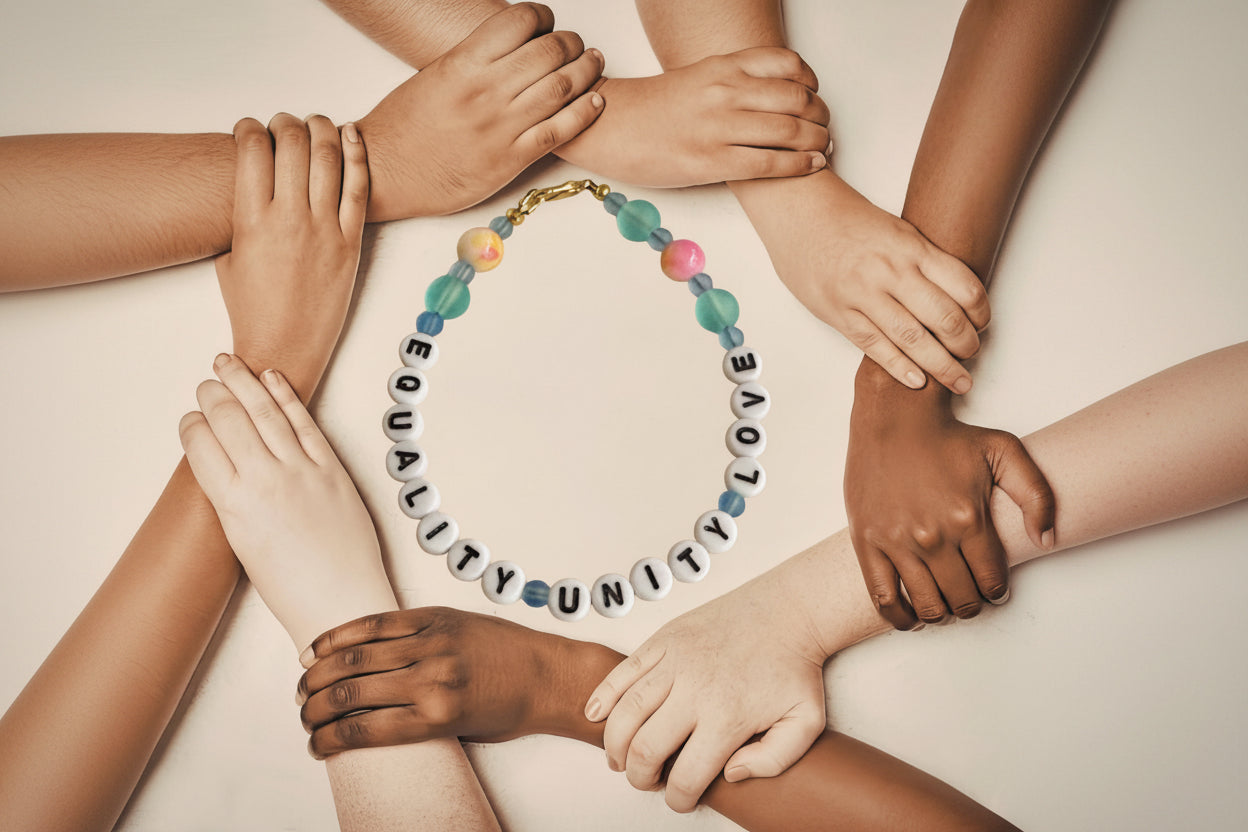 Diverse hands holding each other in unity around a handmade beaded bracelet with letter beads reading Equality Unity Love, representing inclusion, diversity, and love.