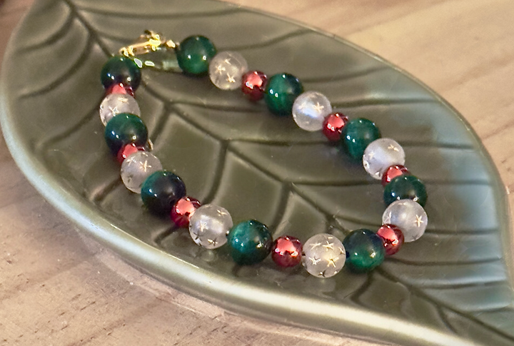 Angled close-up of a green and frosted white star bead bracelet with rose-gold accents and a gold clasp.