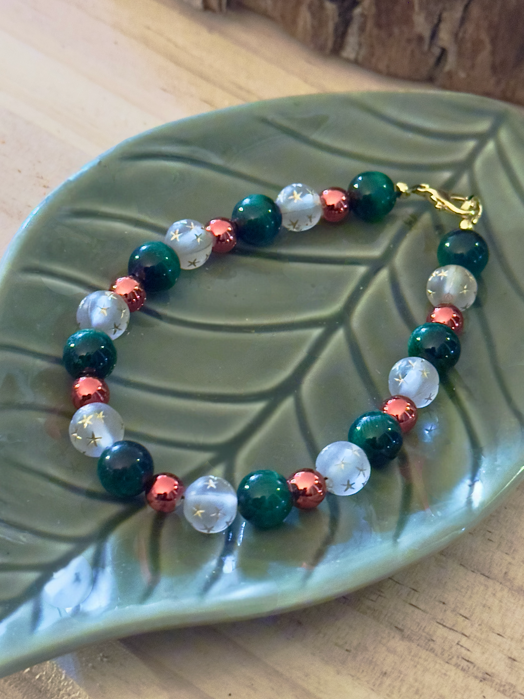 Detailed view of star-etched white beads and glossy green gemstones in a handmade Christmas bracelet.