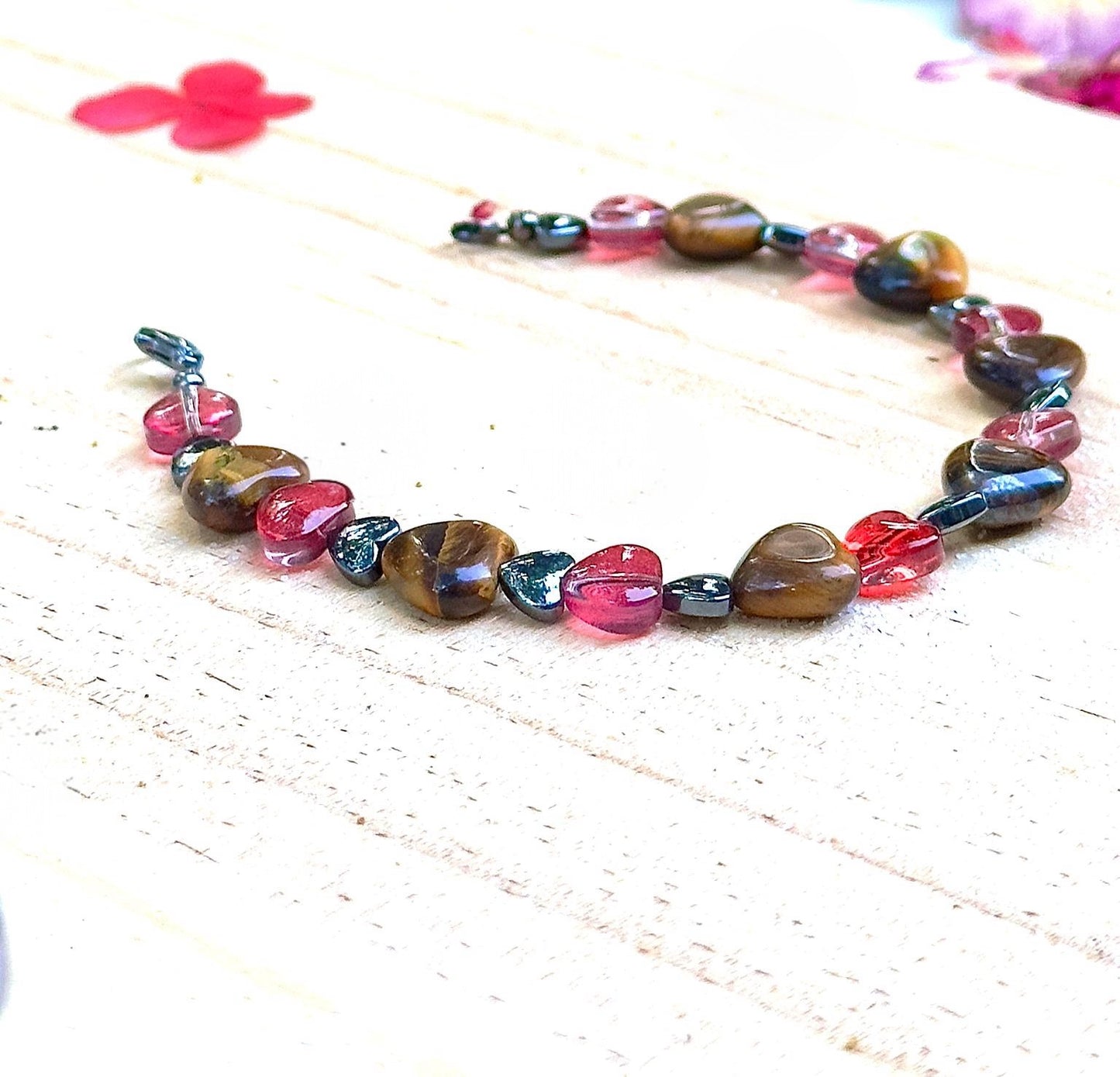 Full view of handmade heart gemstone bracelet with Tiger Eye and pink glass beads on a light surface
