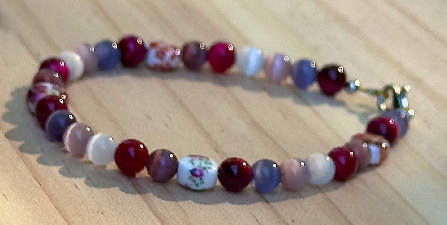     Close-up view of Fearlessly Crimson bracelet featuring floral accent beads and vibrant pride-inspired colors.