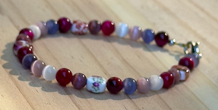     Close-up view of Fearlessly Crimson bracelet featuring floral accent beads and vibrant pride-inspired colors.