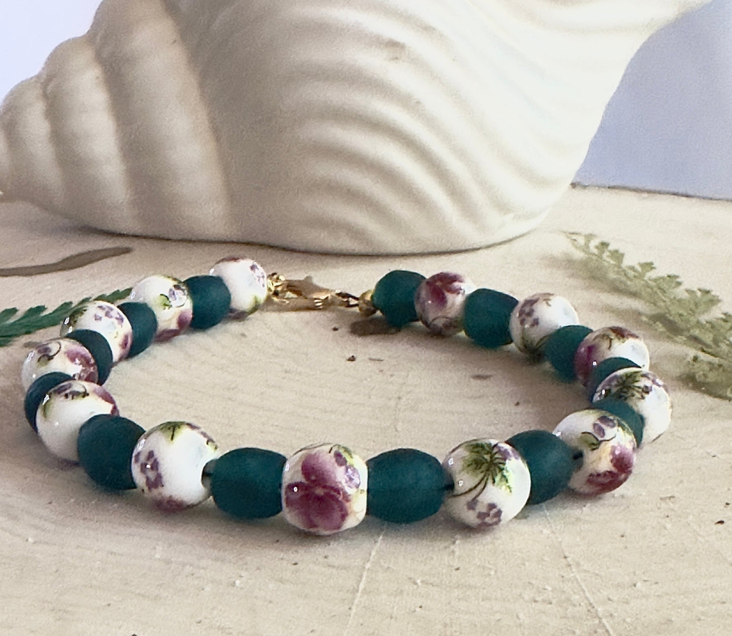 Rose garden themed bracelet laid flat with leaves and neutral background