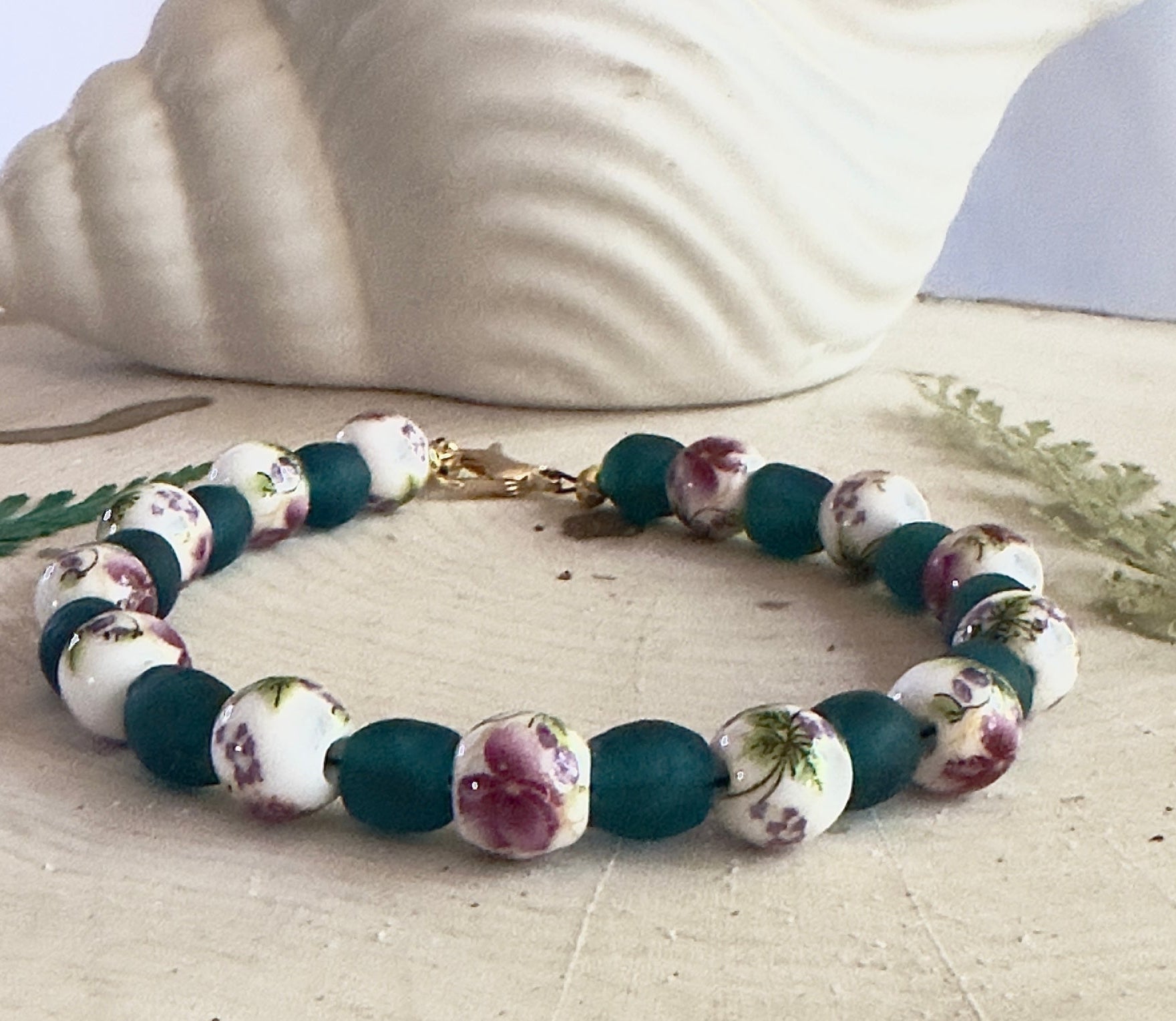 Rose garden themed bracelet laid flat with leaves and neutral background